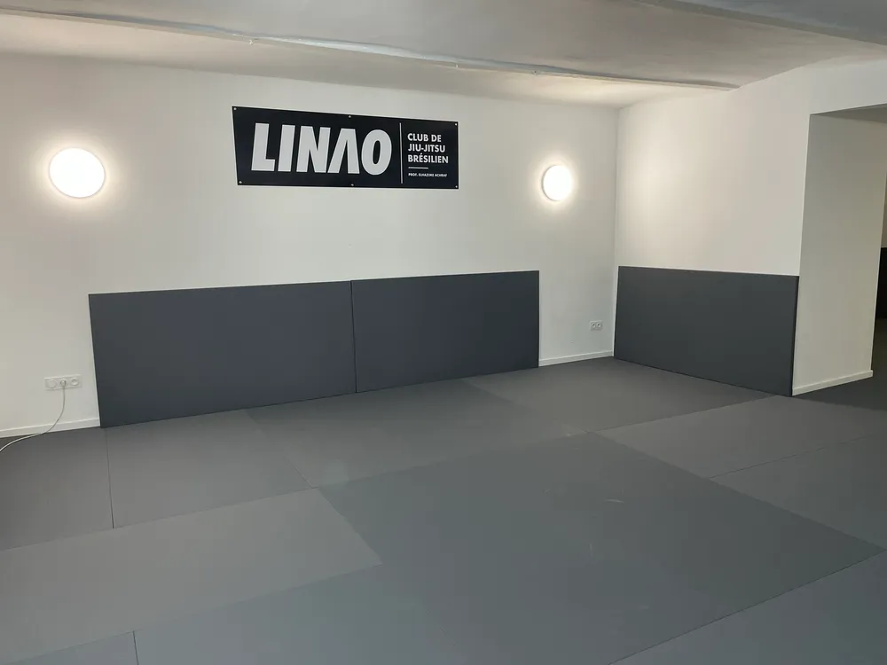 La salle du LINAO Club : tatamis gris et logo LINAO au mur